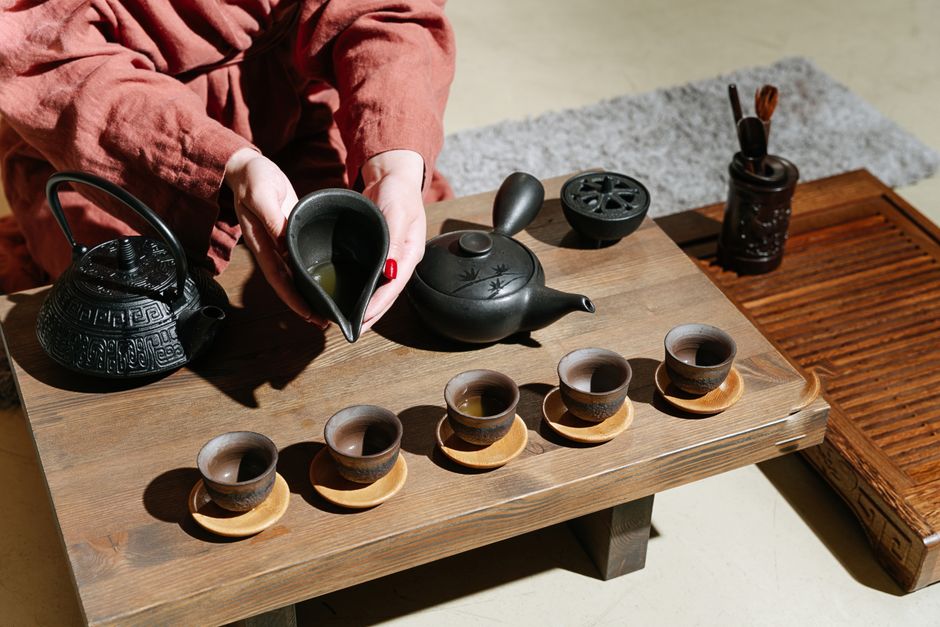 A detailed view of a traditional tea ceremony with clay teapots and cups on a wooden table, showcasing a cultural ritual.