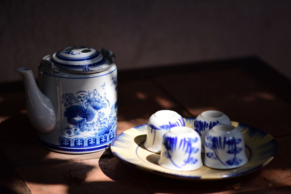 Elegant vintage blue and white teapot with matching cups on a wooden table, creating a cozy classic setting.