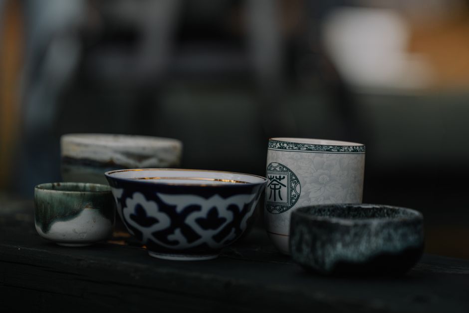 A collection of intricately designed ceramic bowls and cups displayed on a dark surface.